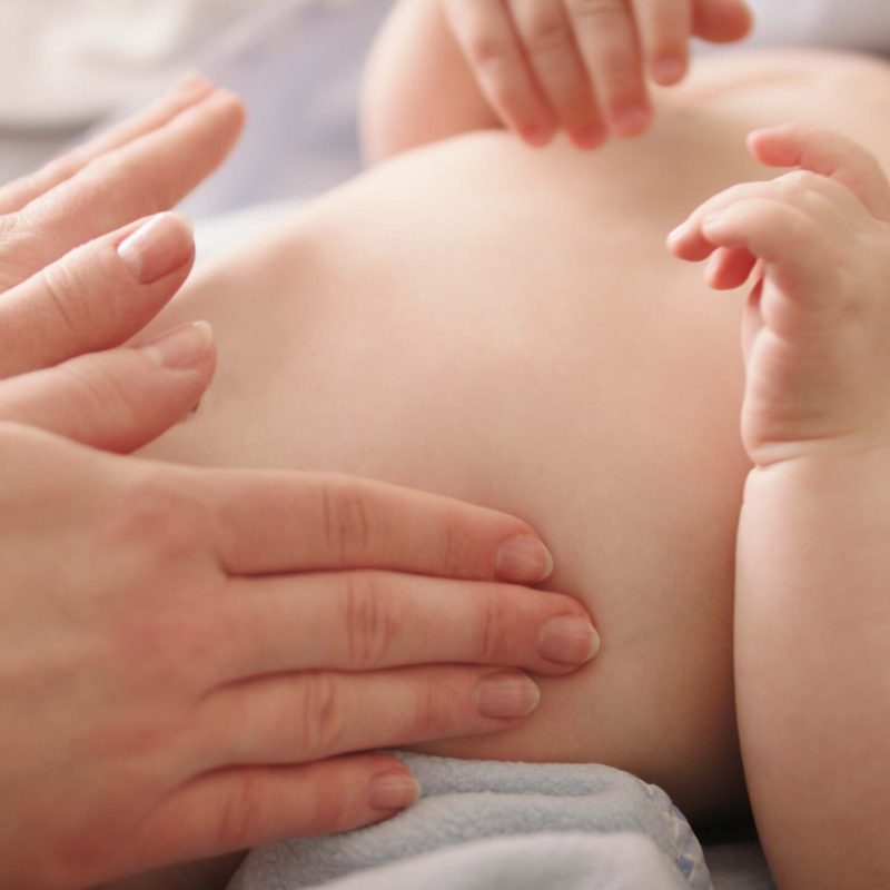 Mother massaging baby tummy. Baby skin care and development concept.
